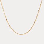 Gold chain necklace on a light gray background