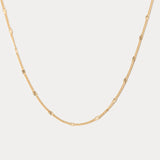 Gold chain necklace on a light gray background