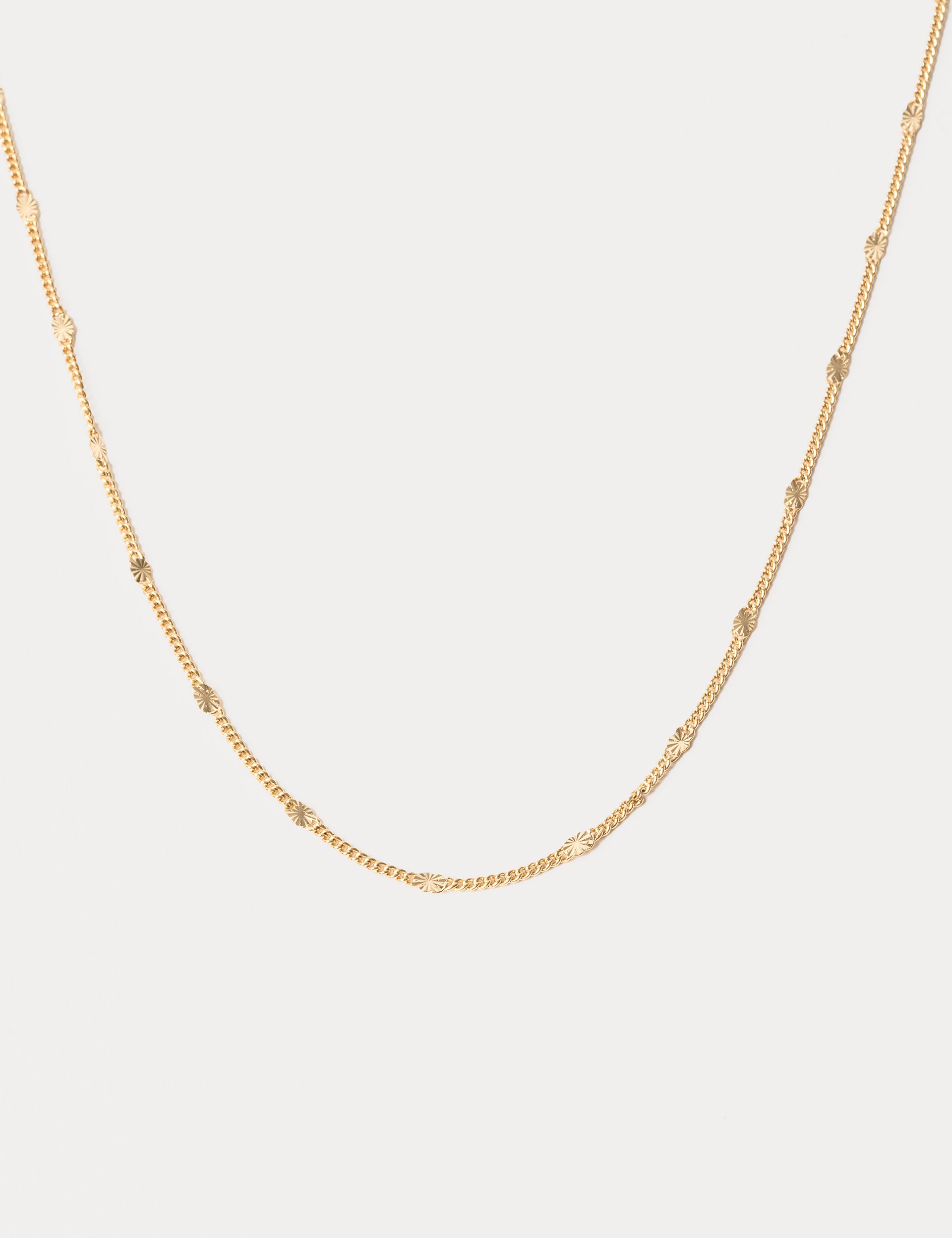 Gold chain necklace on a light gray background
