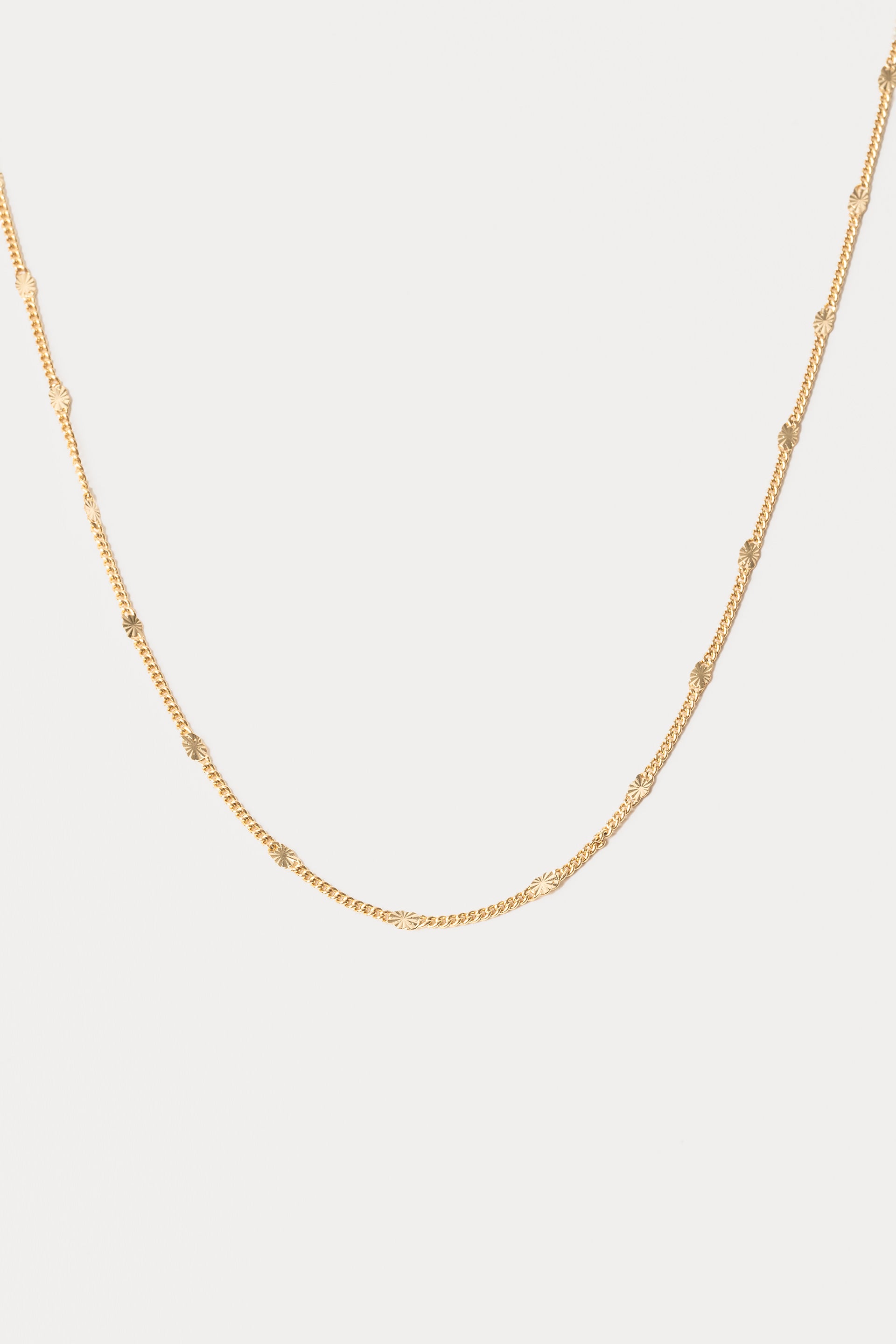 Gold chain necklace on a light gray background