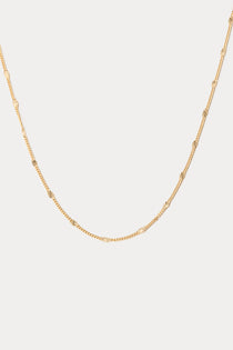 Gold chain necklace on a light gray background