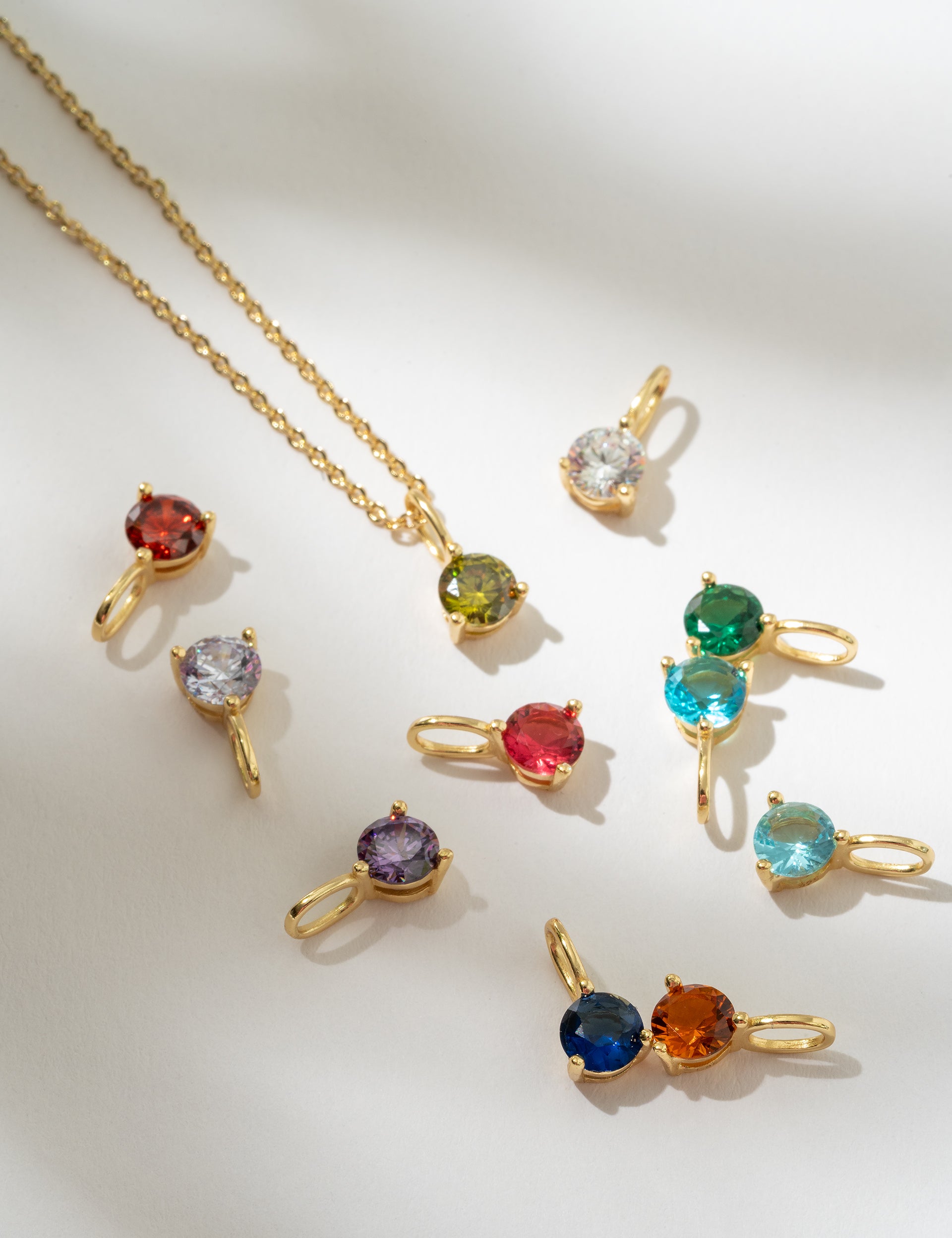 Gold necklaces with multicolored gemstones on a white background