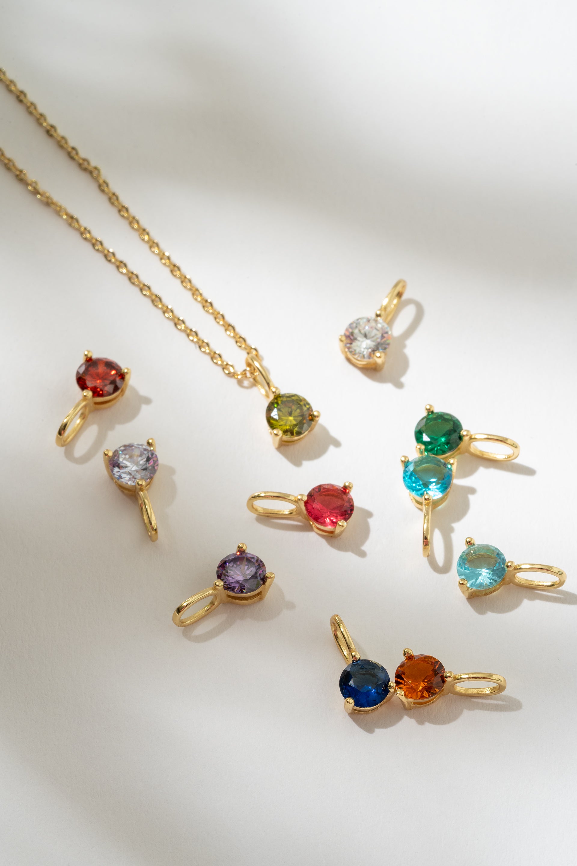 Gold necklaces with multicolored gemstones on a white background