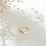 Gold ring on a white surface with delicate flowers