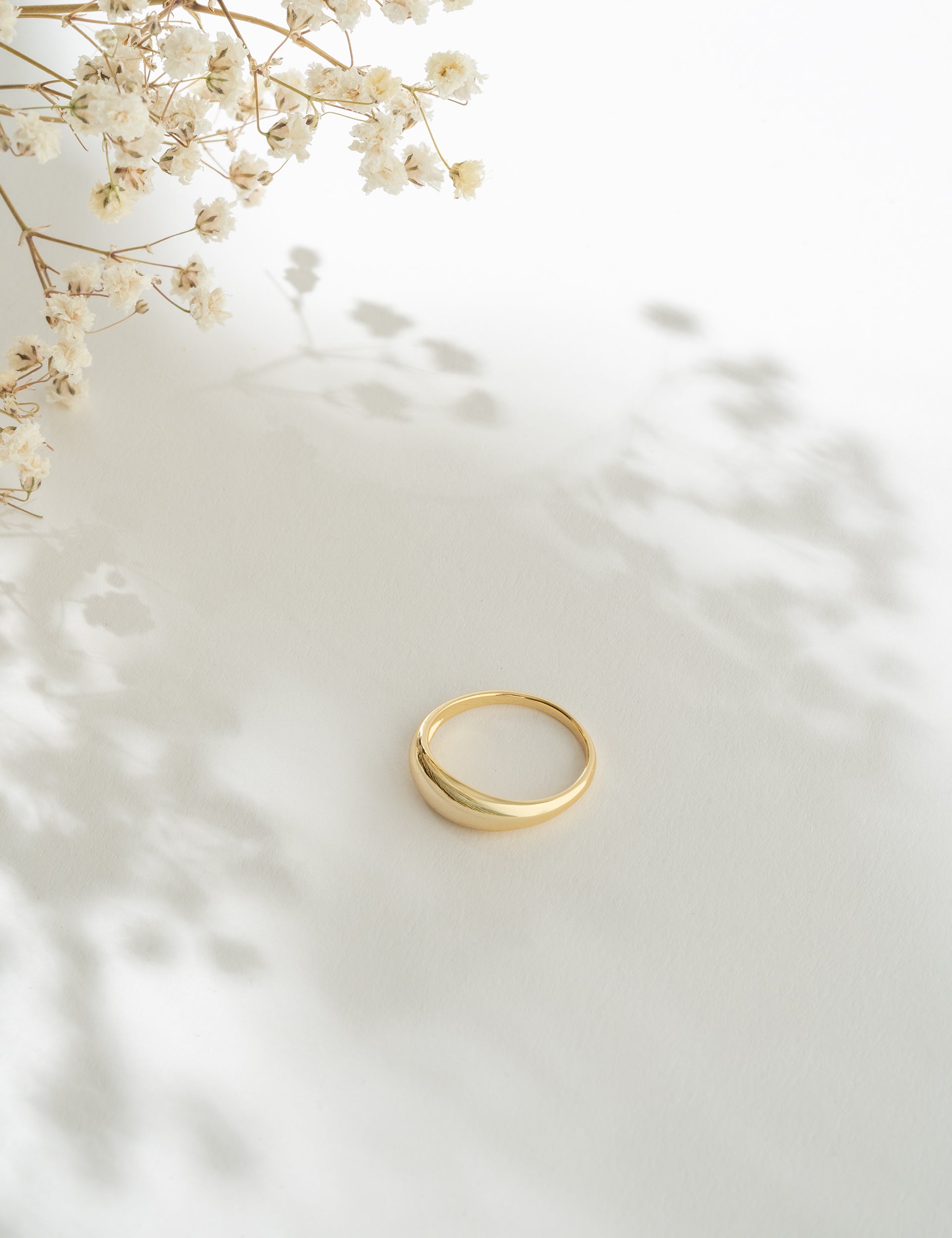 Gold ring on a white surface with delicate flowers