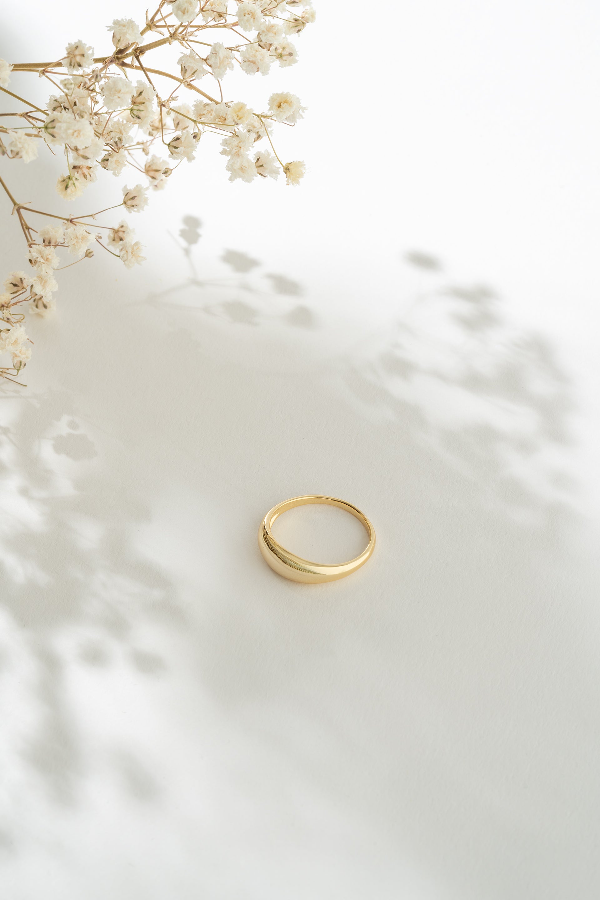 Gold ring on a white surface with delicate flowers