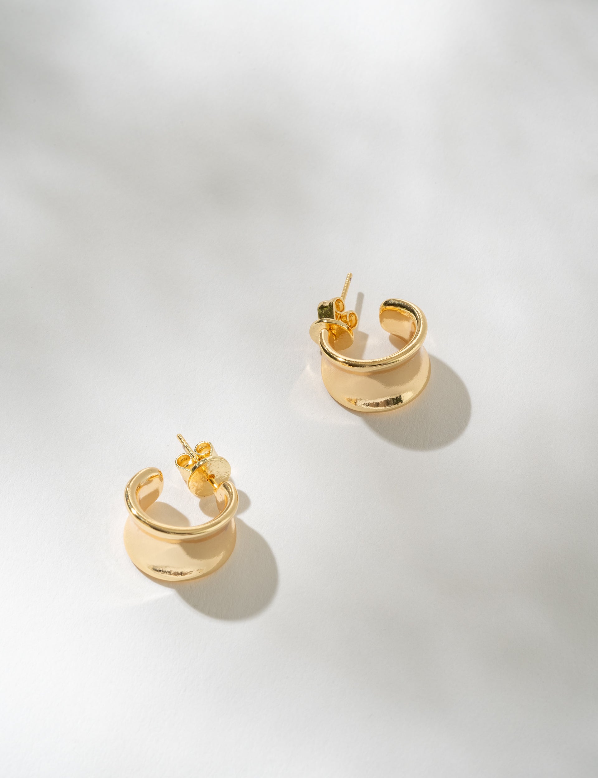 Gold hoop earrings on a light gray background