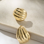 Gold earrings on a beige jewelry dish