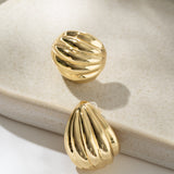 Gold earrings on a beige jewelry dish