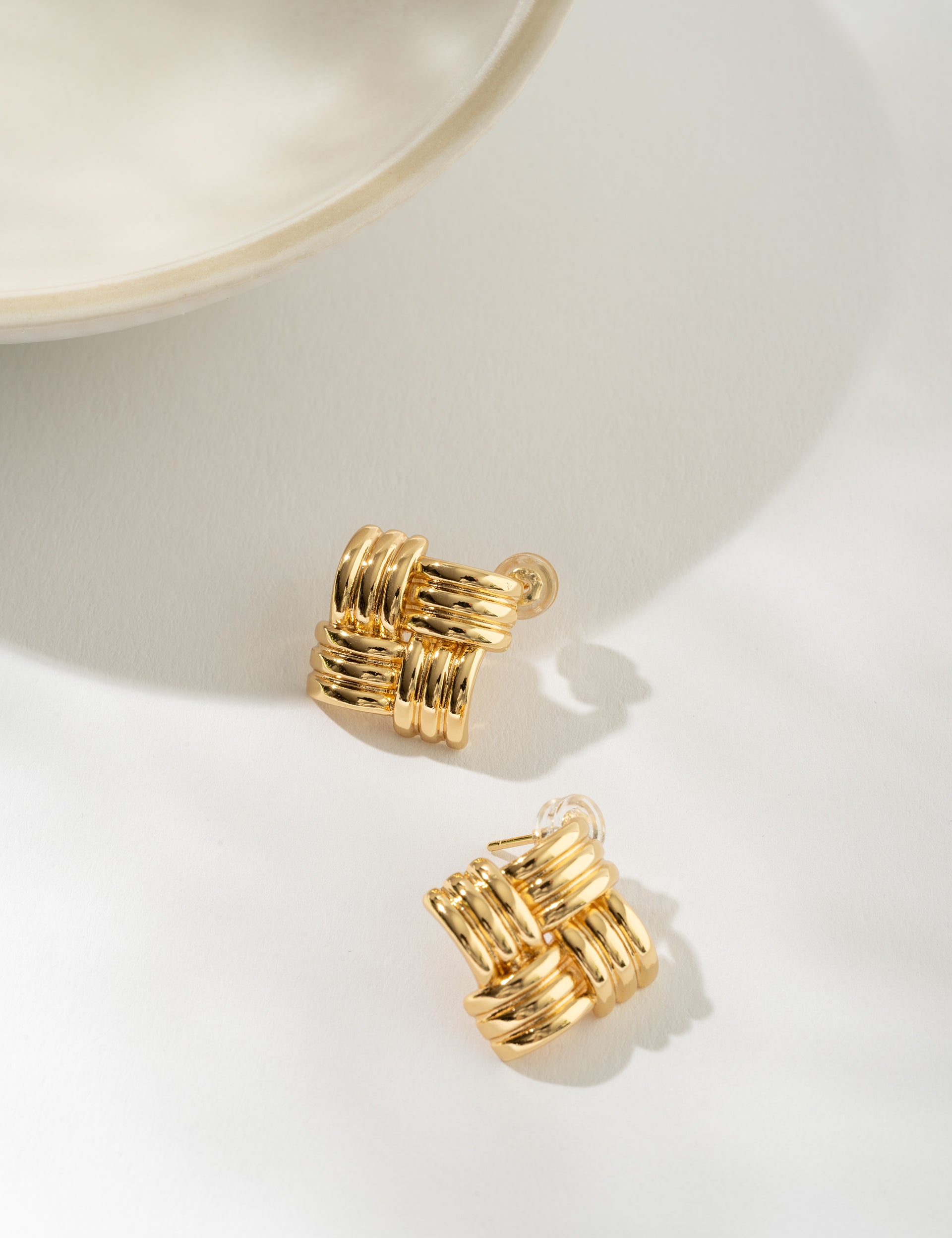 Gold basketweave earrings on a white surface