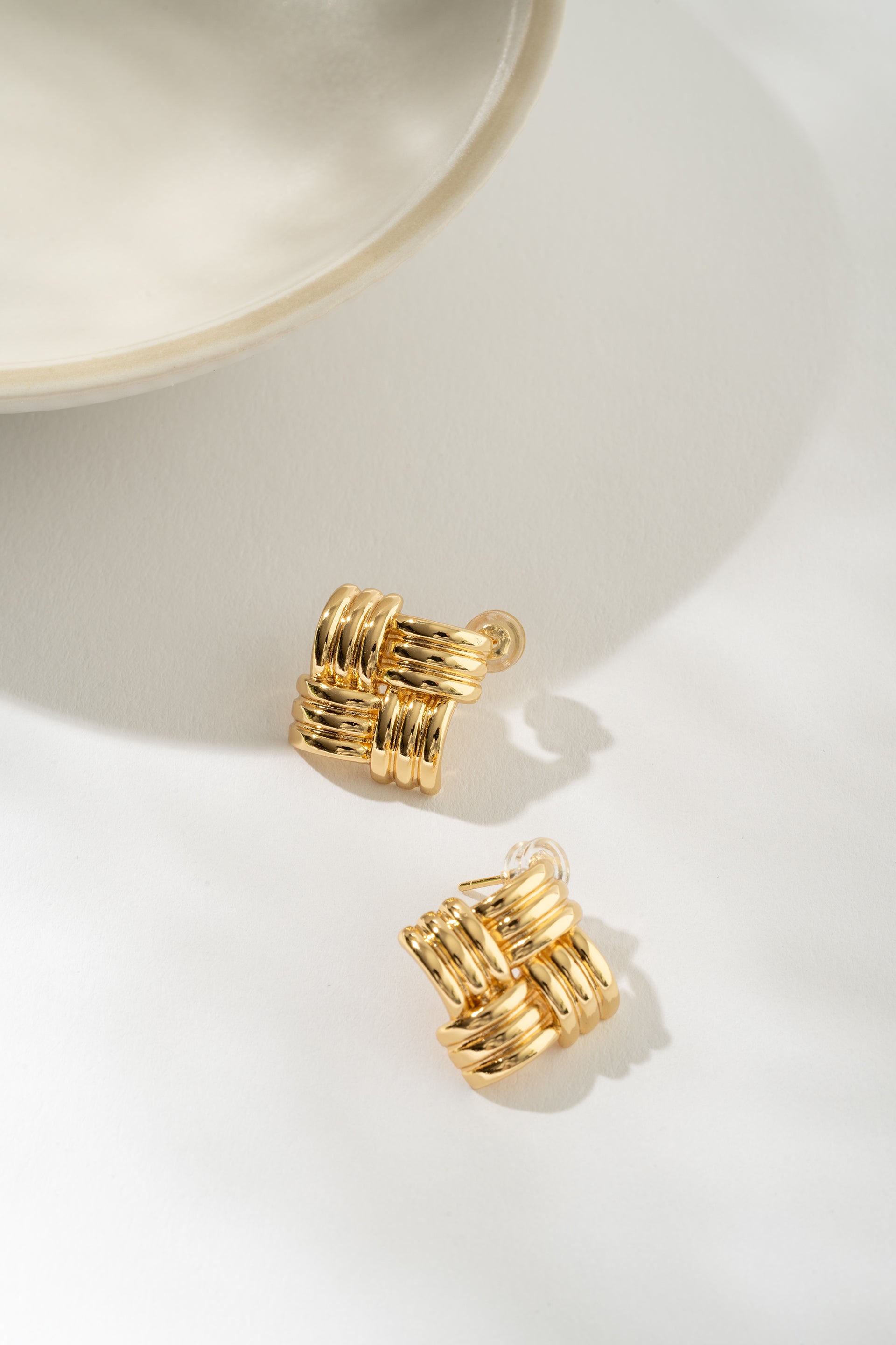 Gold basketweave earrings on a white surface