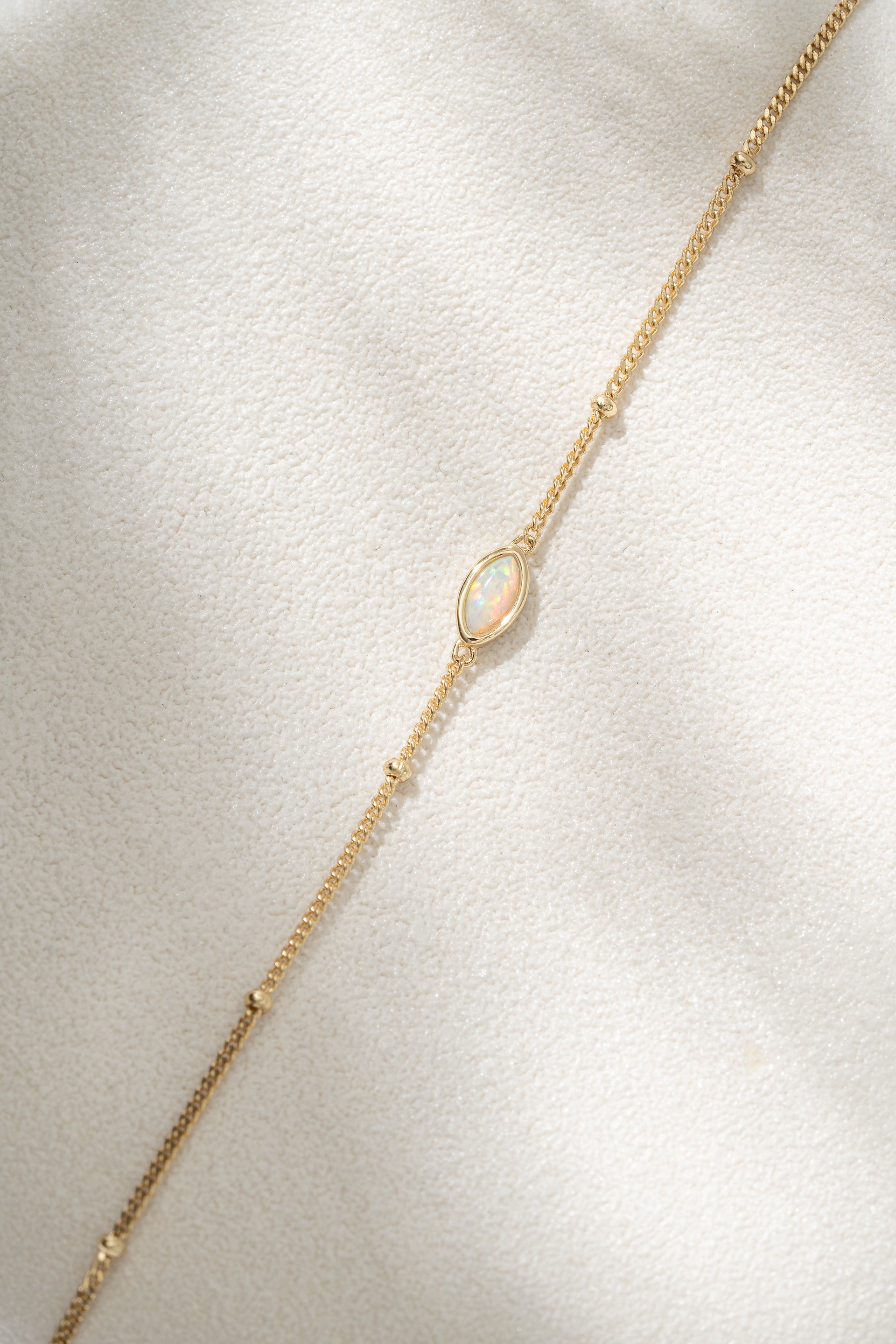 Gold bracelet with a delicate chain on a light gray background