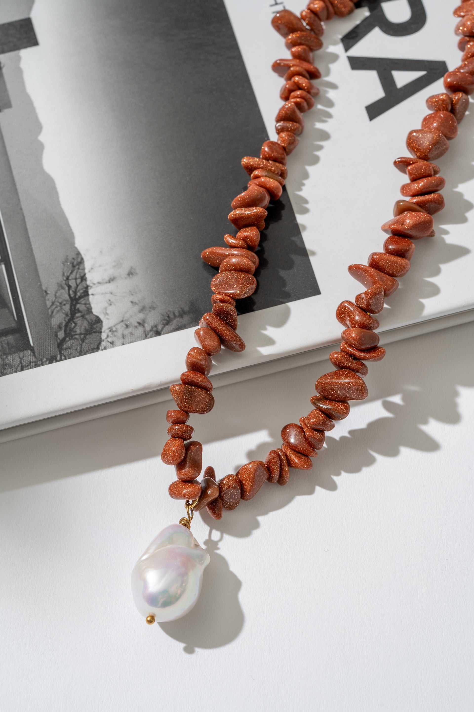 Necklace with red beads and a pearl pendant on a white surface