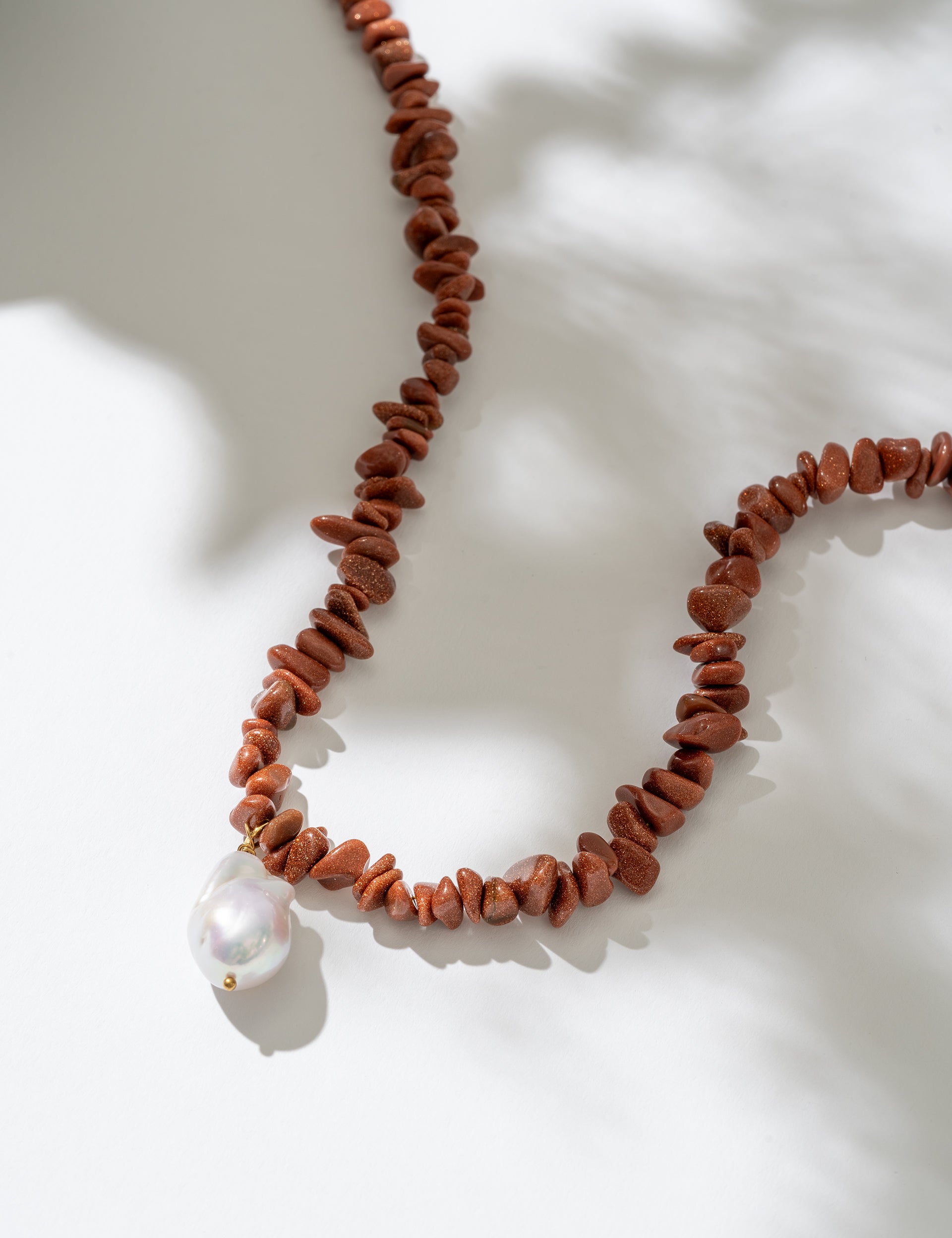 Necklace with red beads and a white pearl on a light background