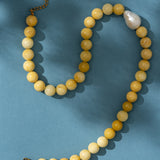 Beaded yellow necklace with a pearl on a blue background