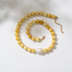Yellow beaded necklace with a pearl pendant on a white background