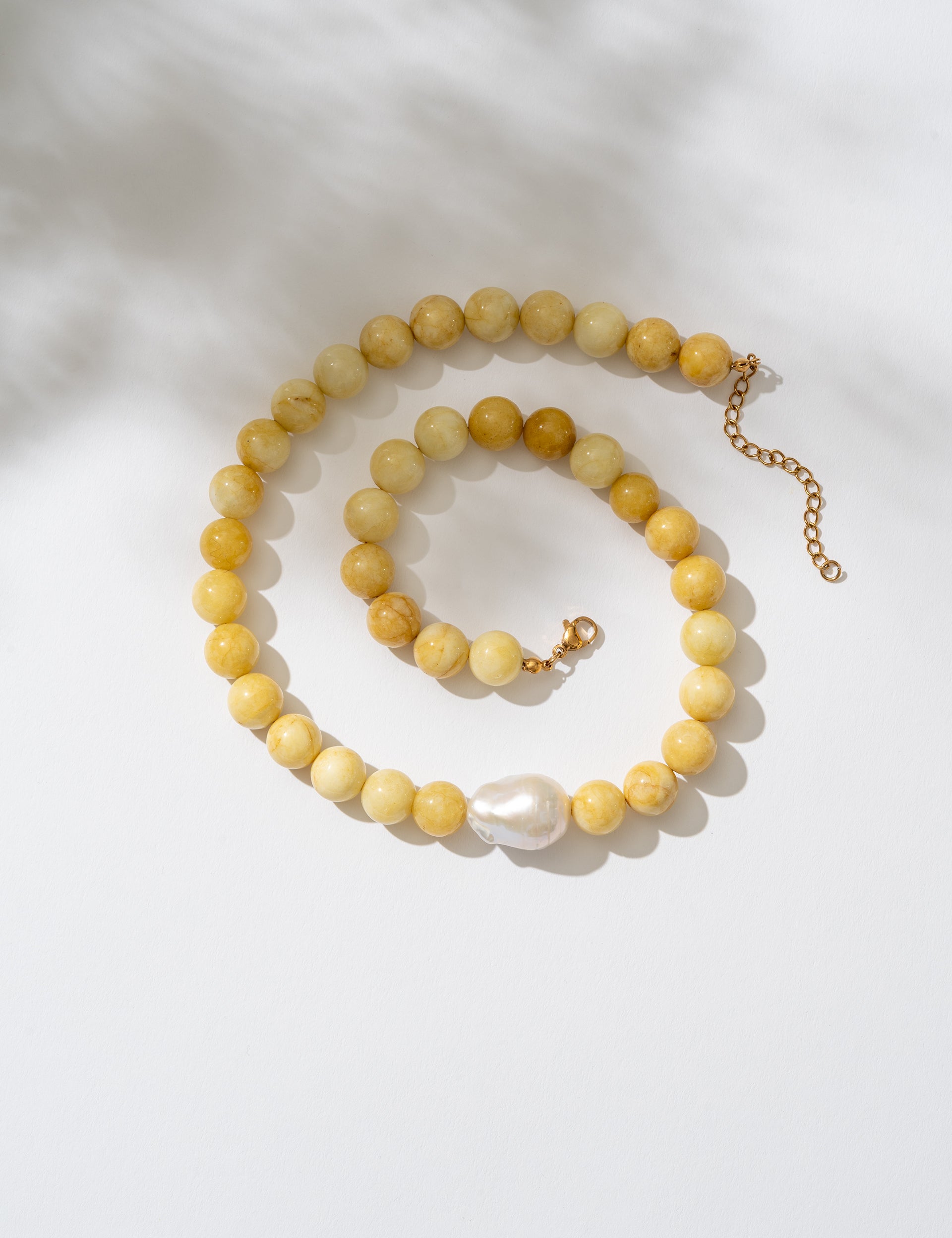 Yellow beaded necklace with a pearl pendant on a white background