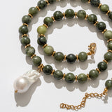 Green beaded necklace with a gold chain and white pendant on a light background