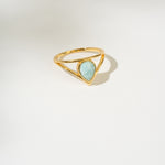 Gold ring with a triangular larimar gemstone on a white background