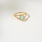 Gold ring with a triangular larimar gemstone on a white background