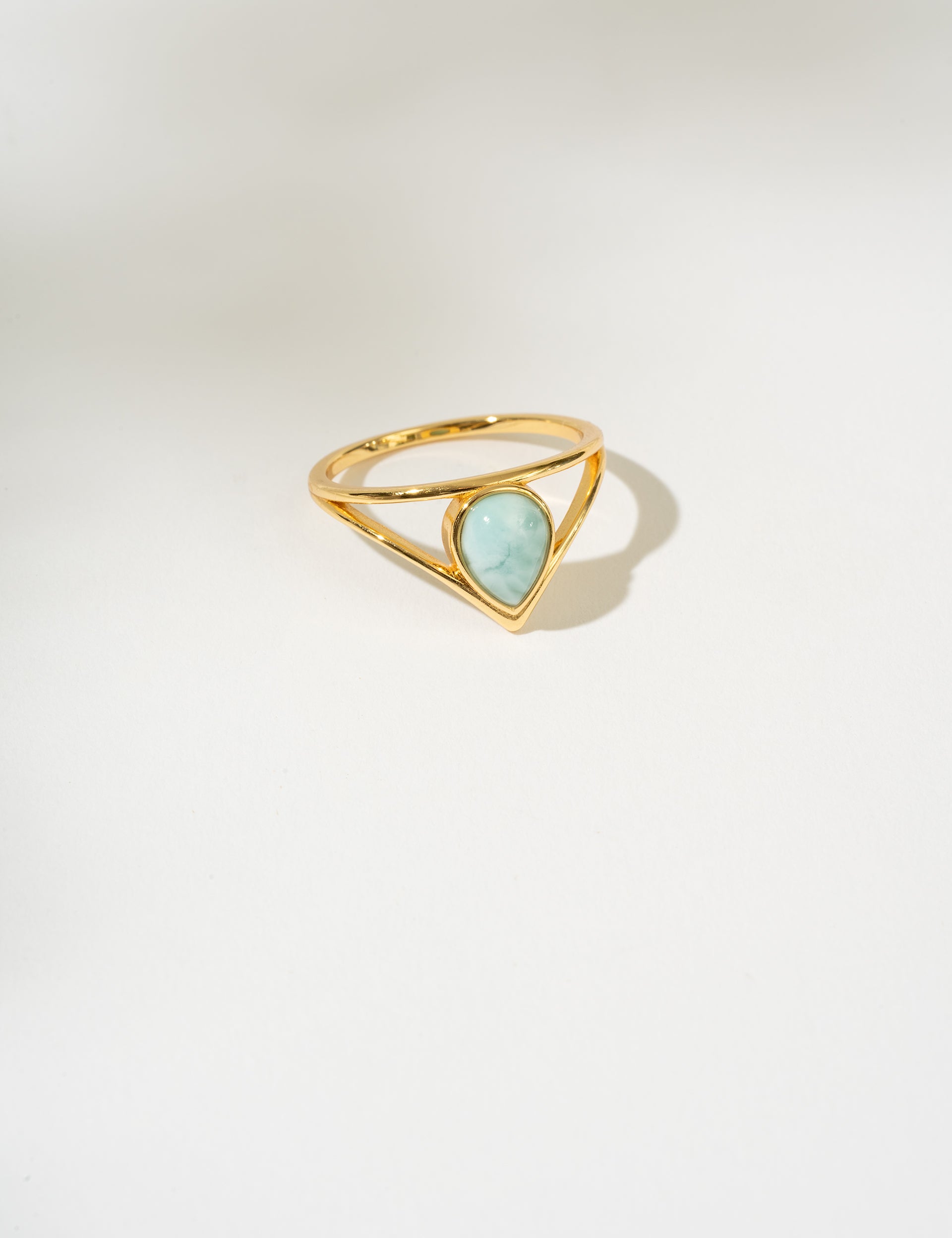 Gold ring with a triangular larimar gemstone on a white background