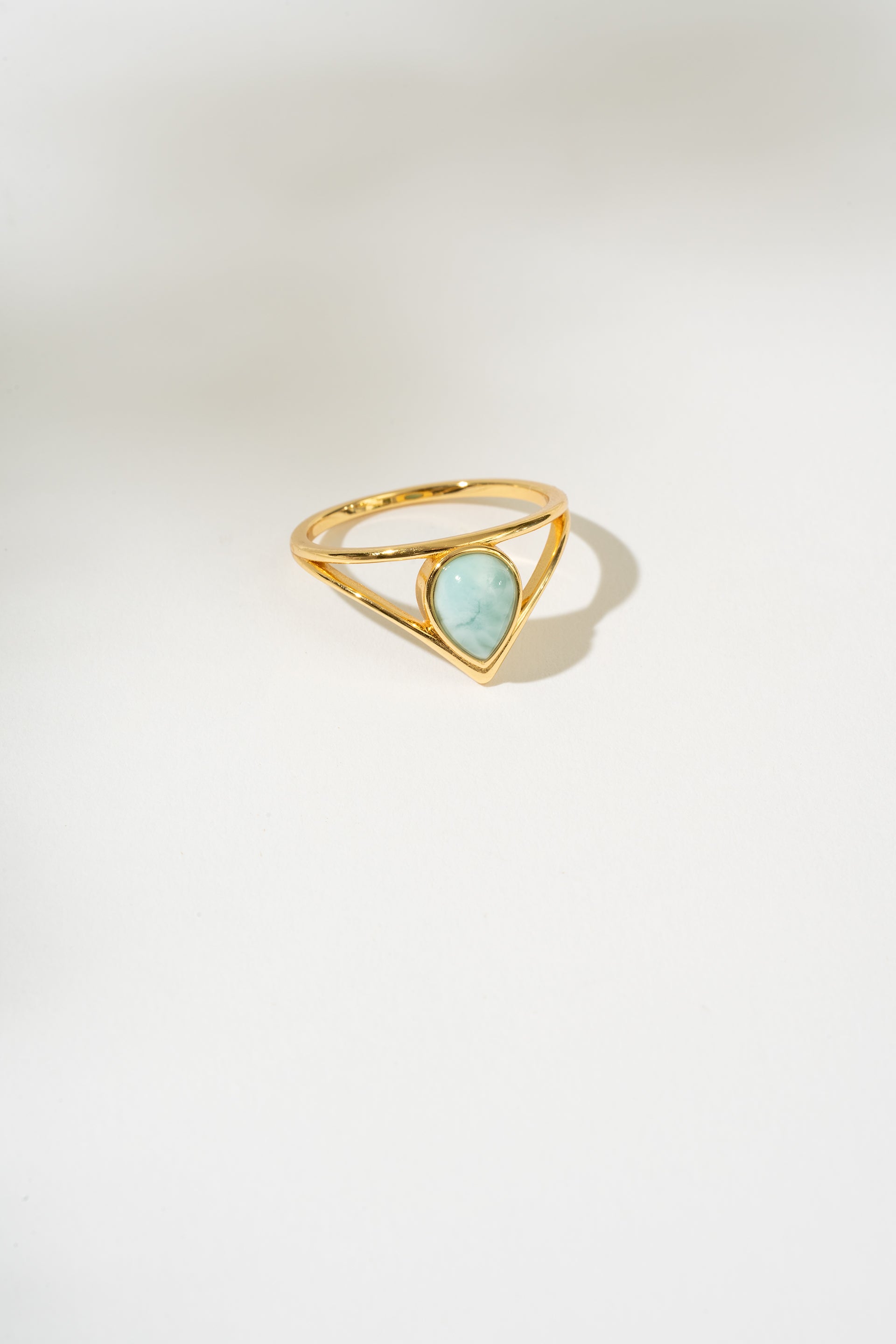 Gold ring with a triangular larimar gemstone on a white background