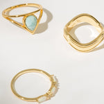 Three gold rings with different designs on a light background