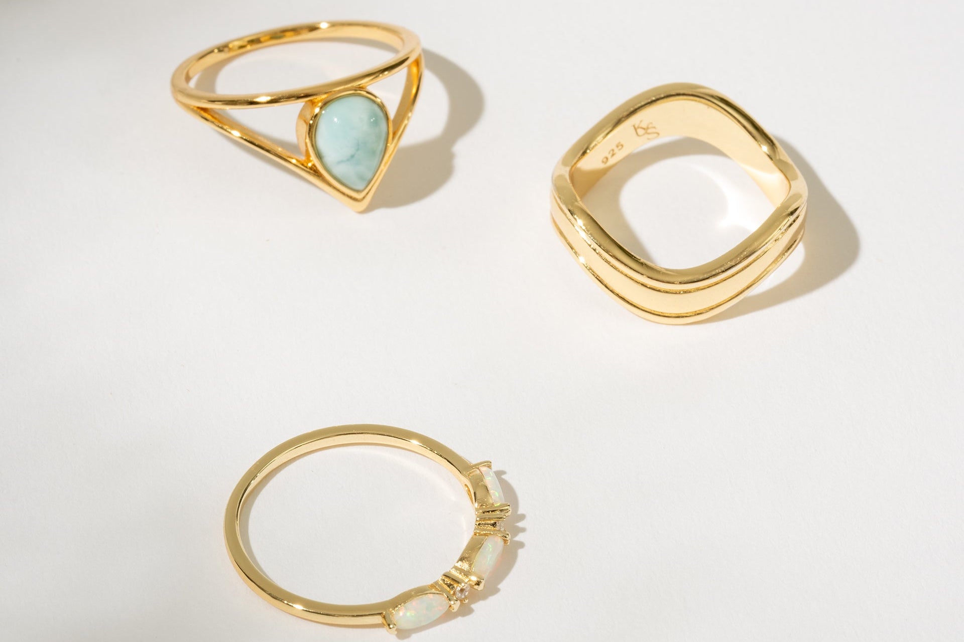 Three gold rings with different designs on a light background
