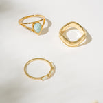 Three gold rings with different designs on a light background