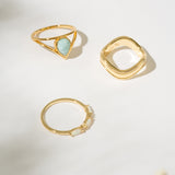 Three gold rings with different designs on a light background