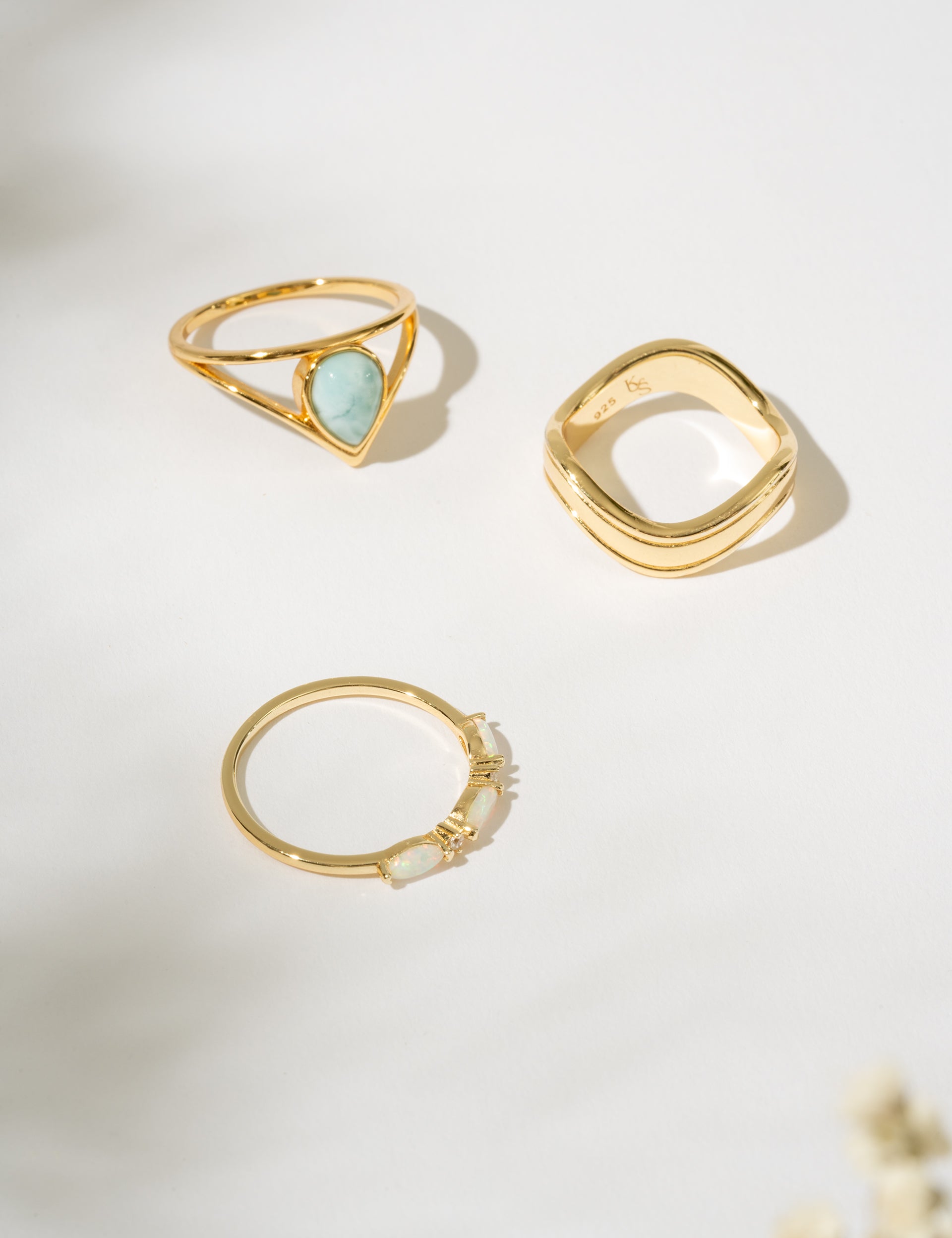 Three gold rings with different designs on a light background