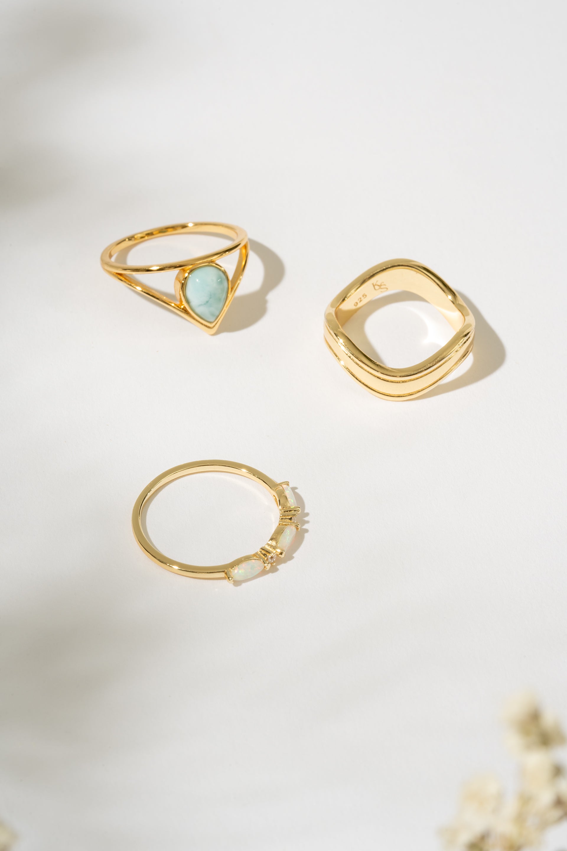 Three gold rings with different designs on a light background