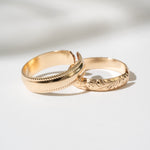 Two gold rings with intricate designs on a light background