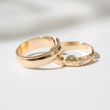 Two gold rings with intricate designs on a light background