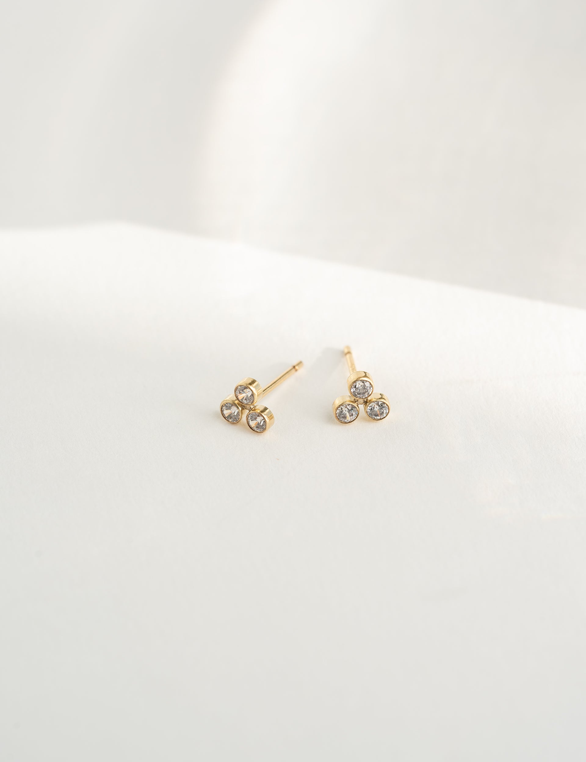 Gold earrings with clear stones on a white background