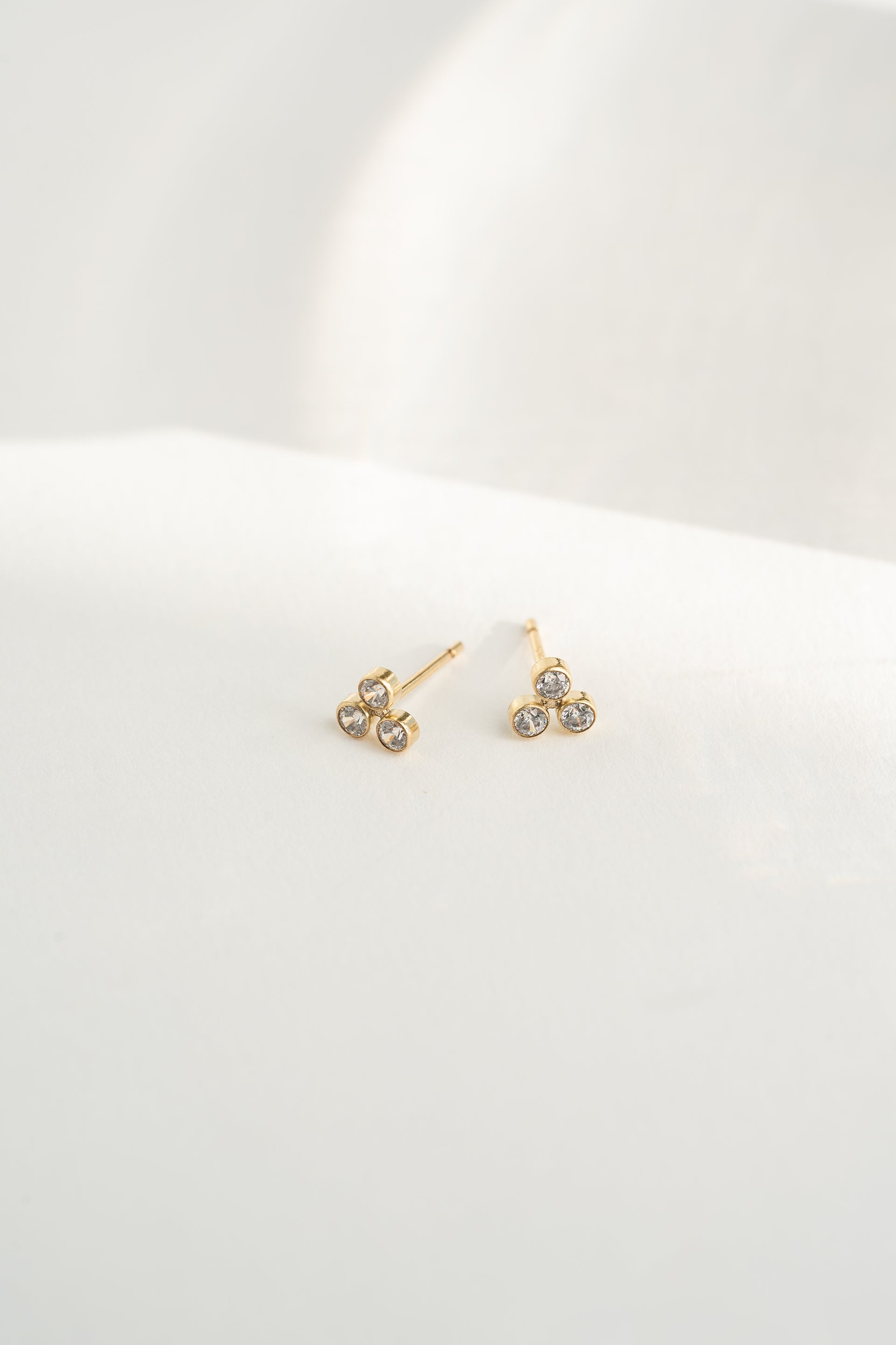 Gold earrings with clear stones on a white background
