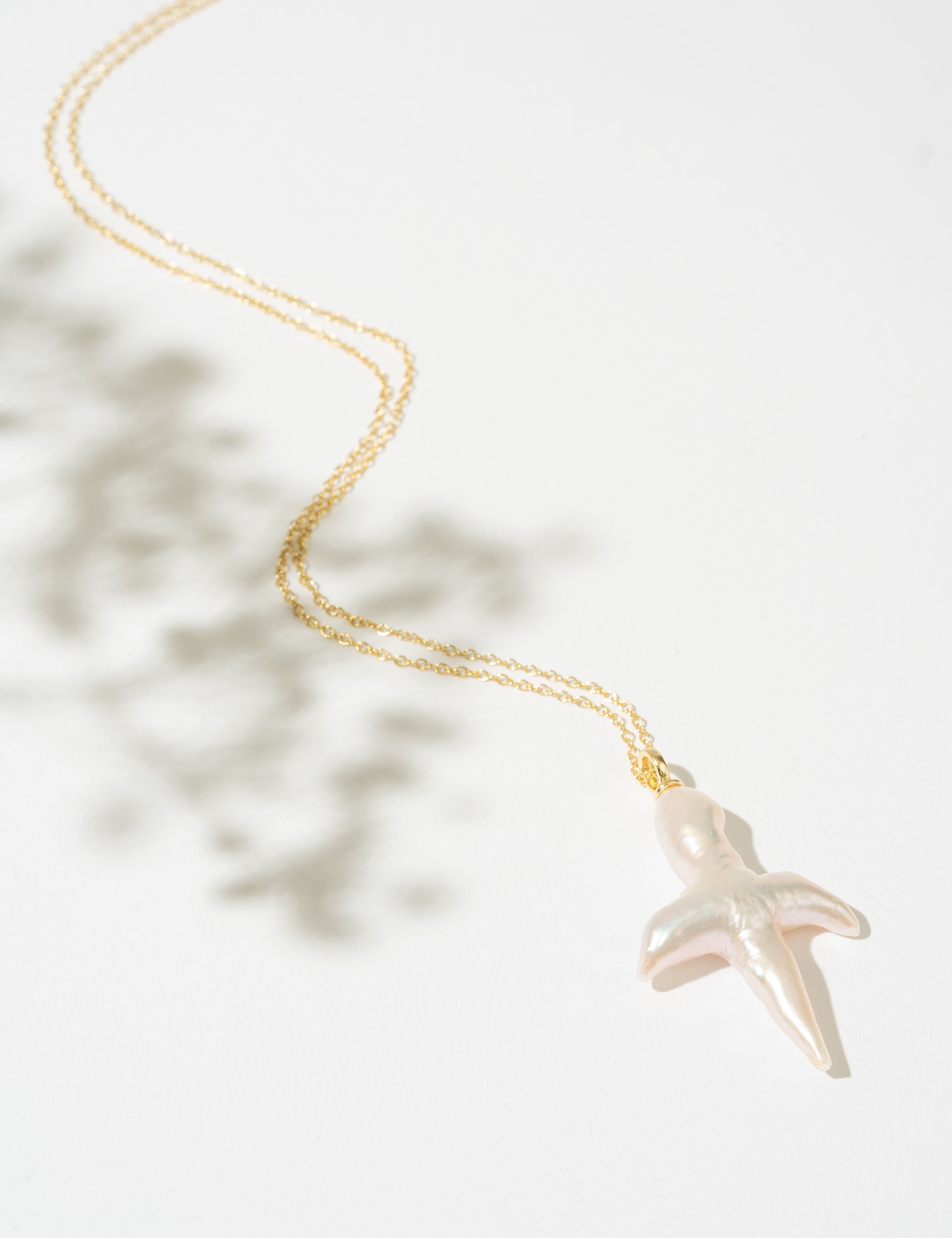 Gold necklace with a pearl cross pendant