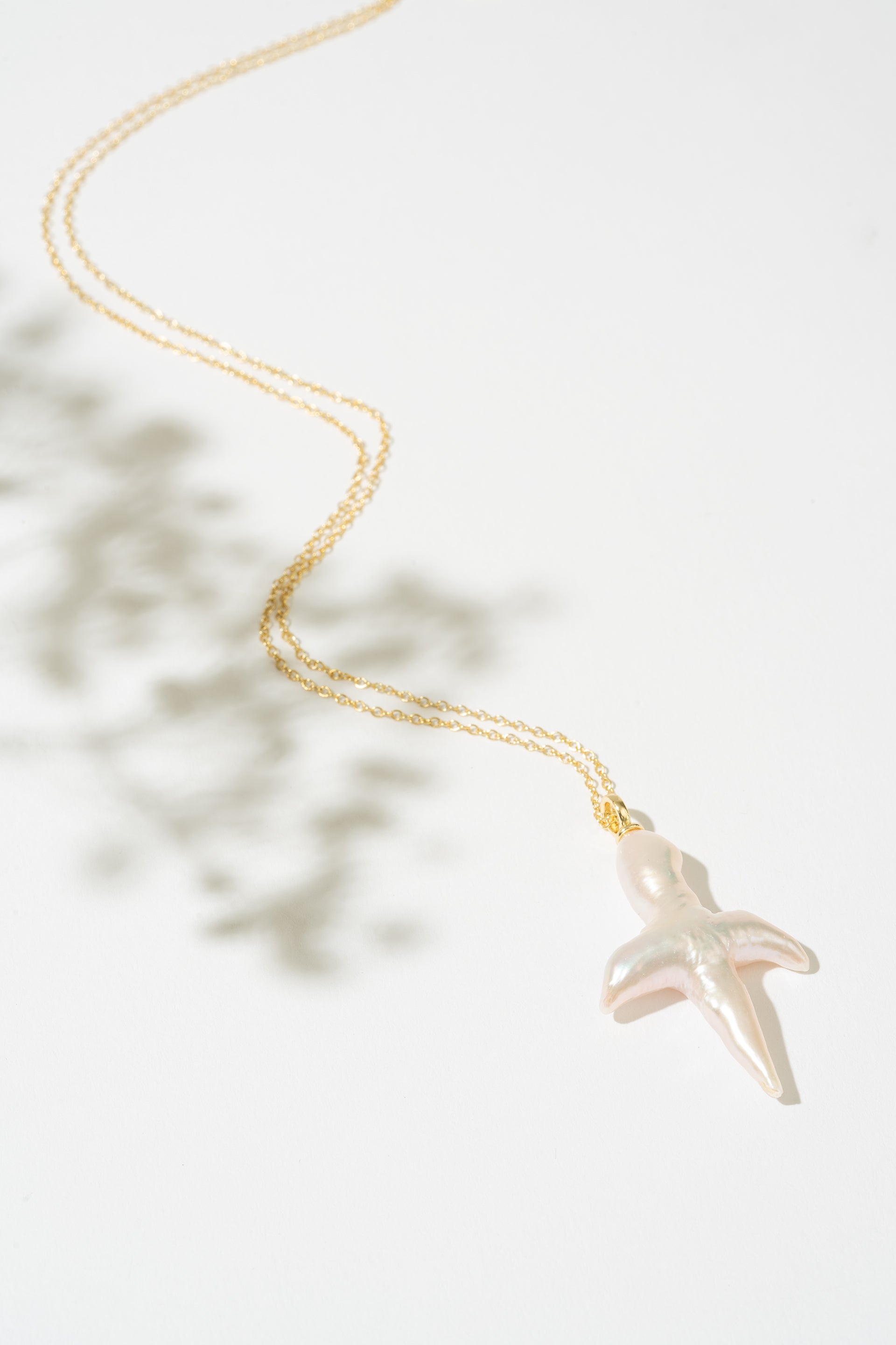 Gold necklace with a pearl cross pendant