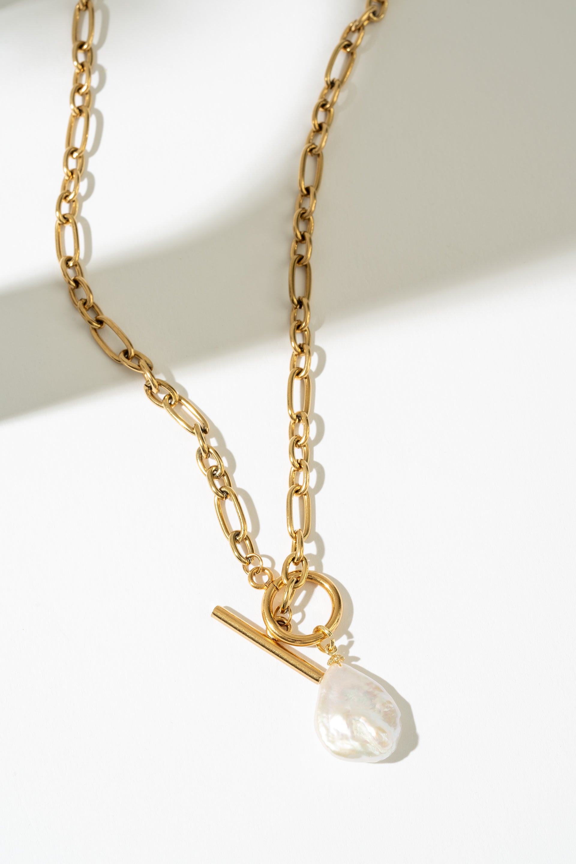 Gold necklace with a pearl pendant on a white background