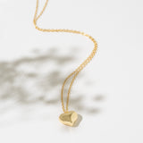 Gold necklace with a heart-shaped pendant on a white background