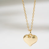 Gold heart-shaped pendant necklace on a light gray background
