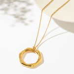 Gold necklace with a circular pendant on a white background