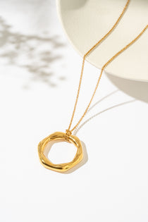 Gold necklace with a circular pendant on a white background