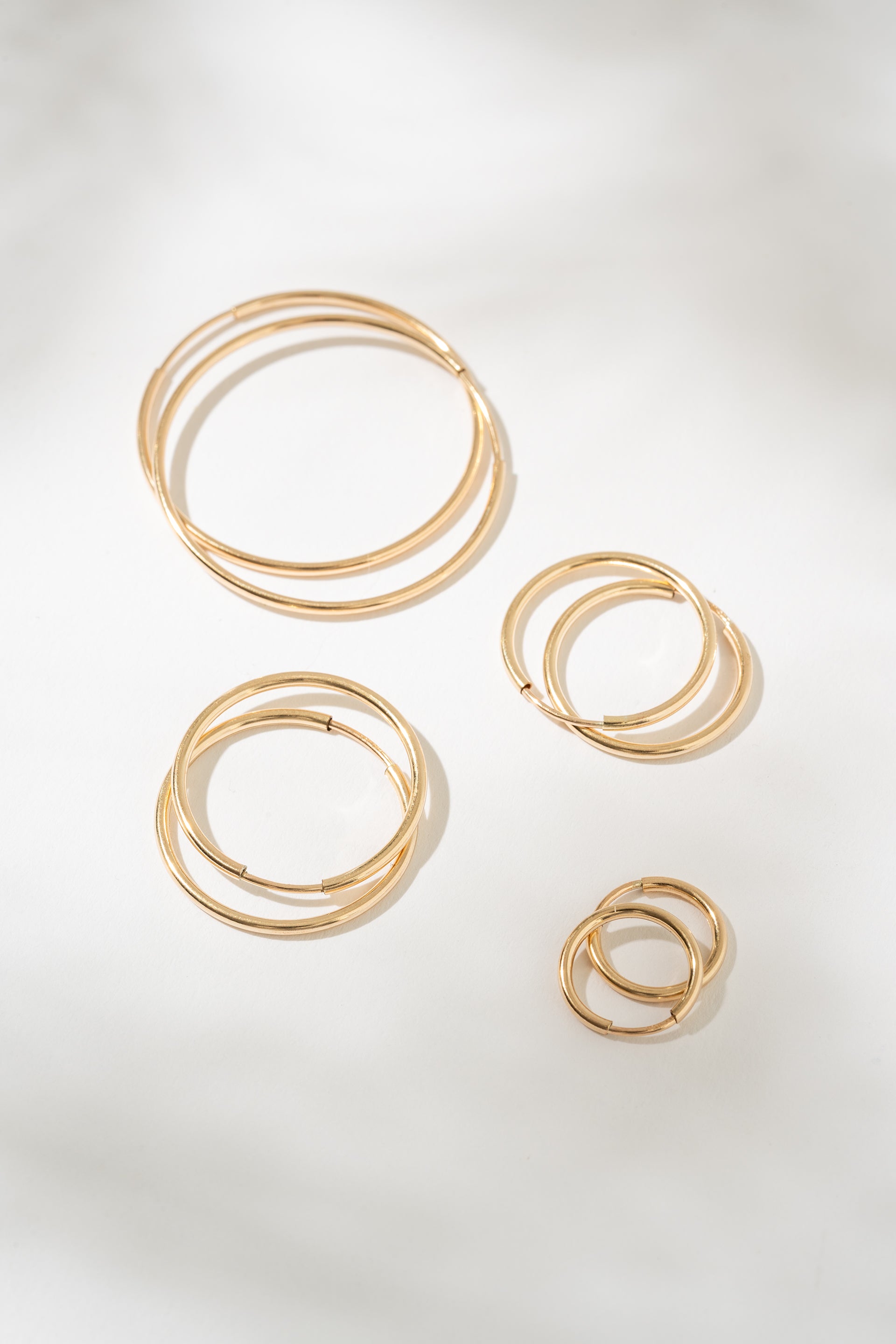 Set of gold hoop earrings on a light gray background