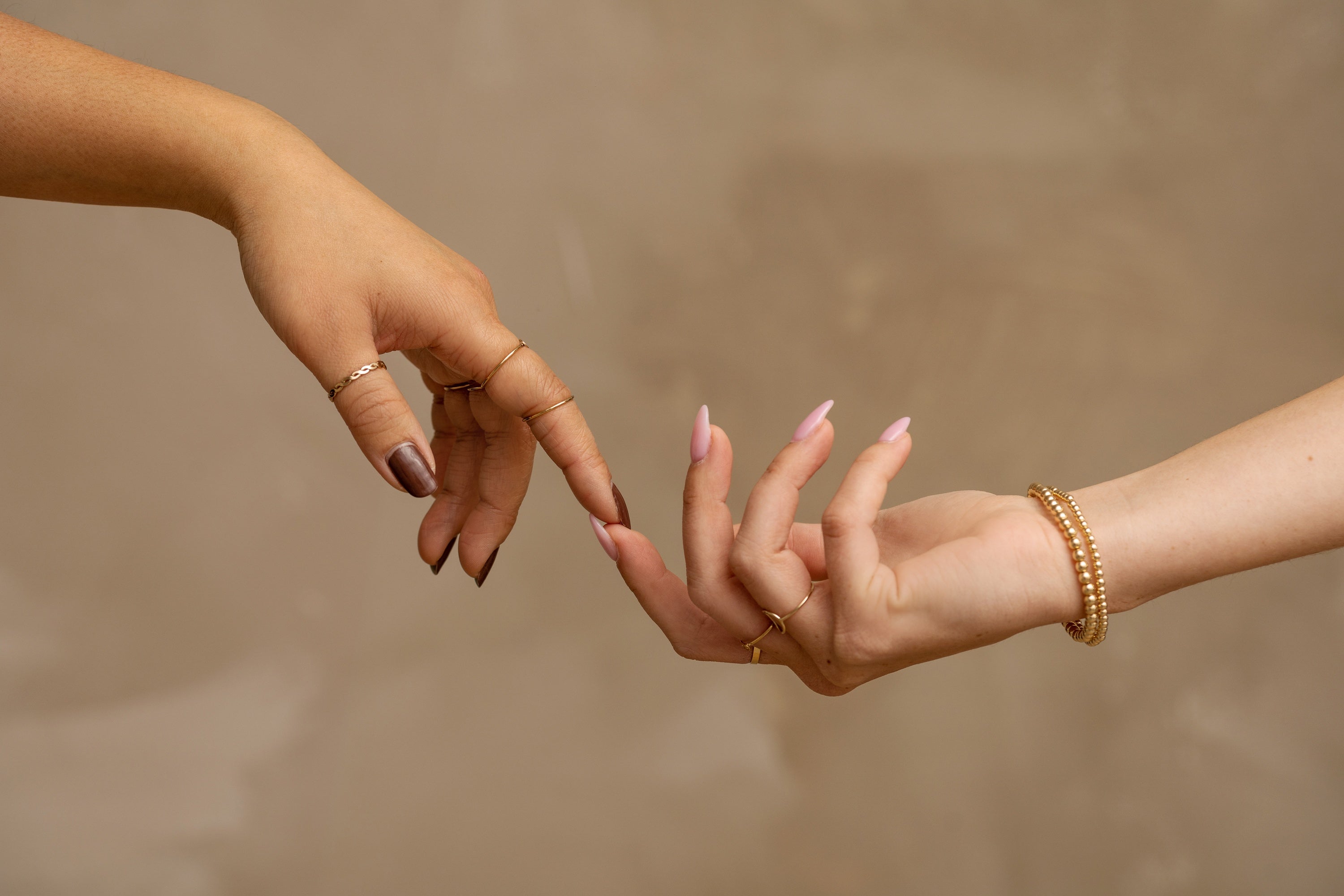 Two hands meeting with gold jewelry