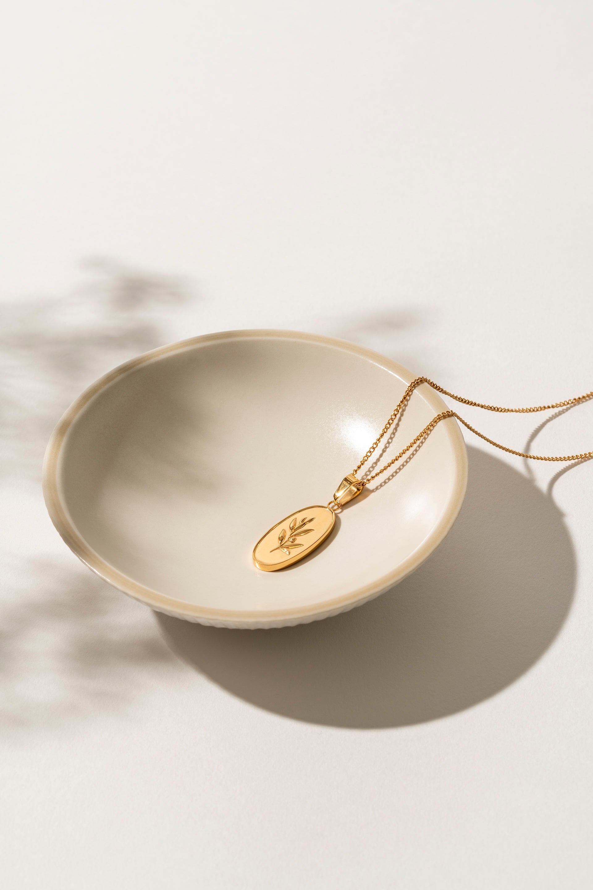 Close-up of the Olivia Necklace showcasing its intricate olive branch design in 18kt gold stainless steel. The fine detailing and warm gold tone create a timeless, elegant piece perfect for everyday wear or special occasions.