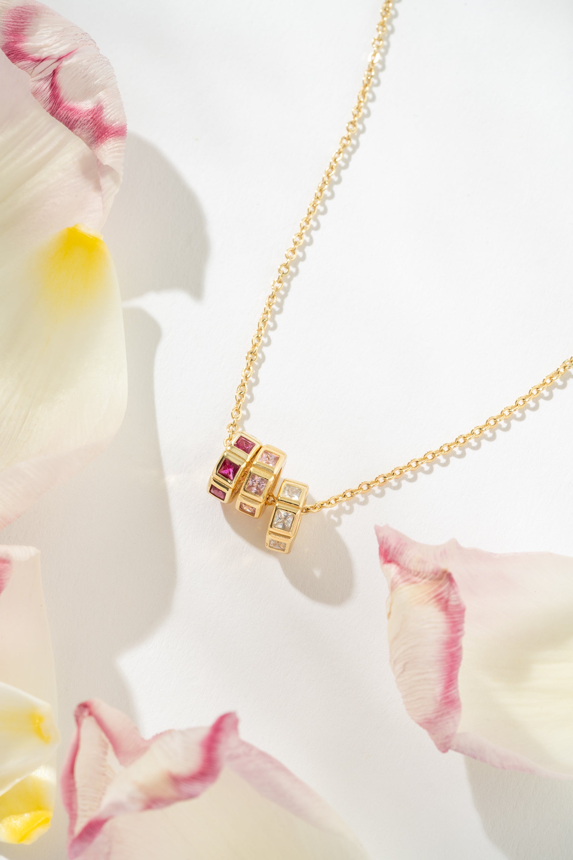 Gold necklace with birthsones on a white background