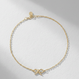 Gold necklace with a bow charm on a light gray background