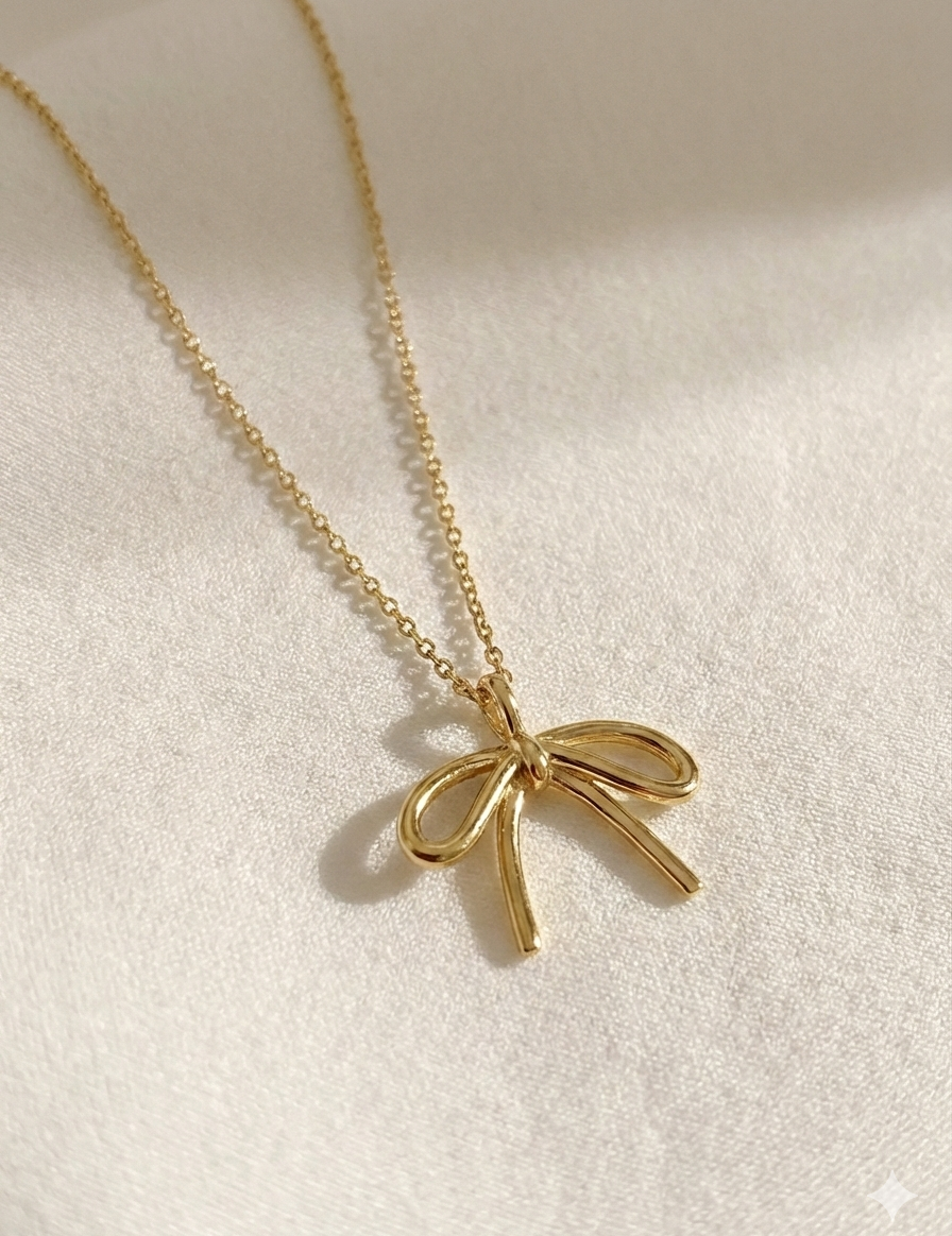 Gold bow-shaped pendant necklace on a light background
