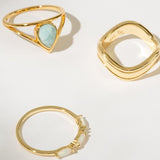 Three gold rings with different designs on a light background